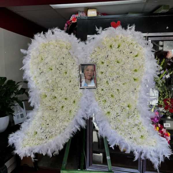 White floral heart-shaped funeral spray with a framed photo in the center