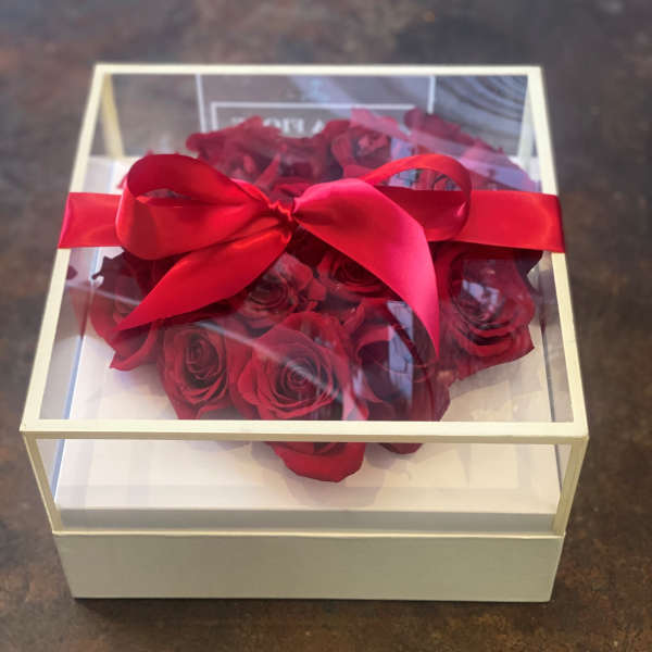 Red roses in a clear gift box tied with a red ribbon