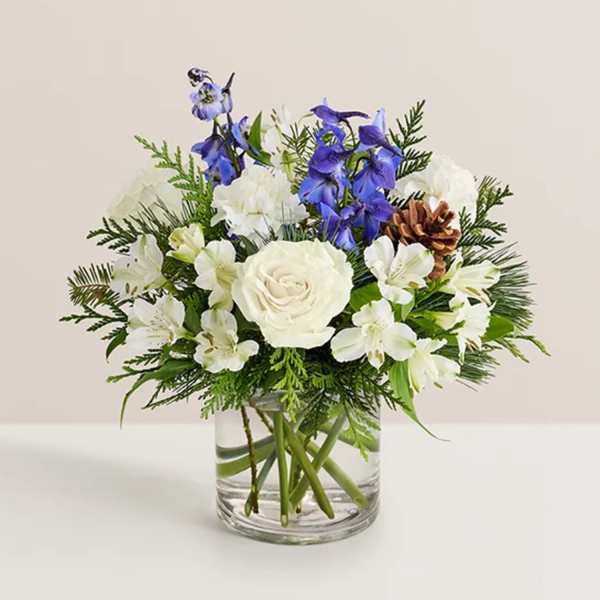 White roses and blue flowers in a clear glass vase