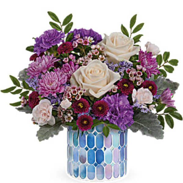 Purple and white flower arrangement in a blue mosaic vase