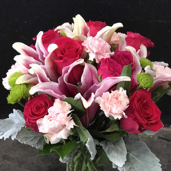 Bouquet of pink roses, calla lilies, and carnations in a glass vase