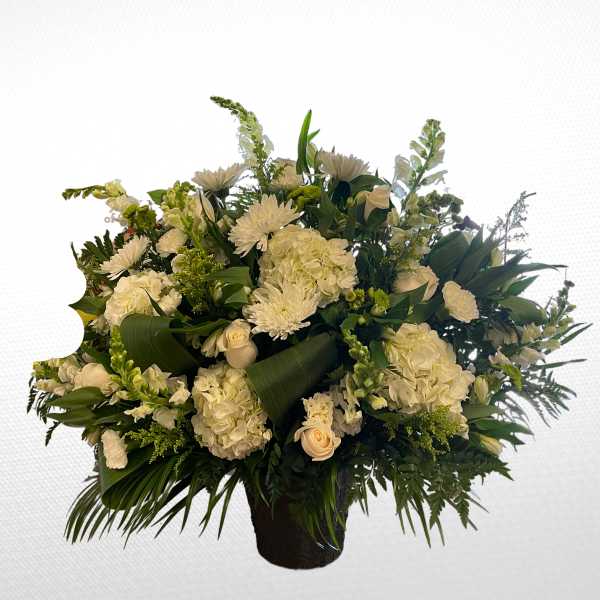 White floral arrangement in a black vase with mixed blooms and greenery