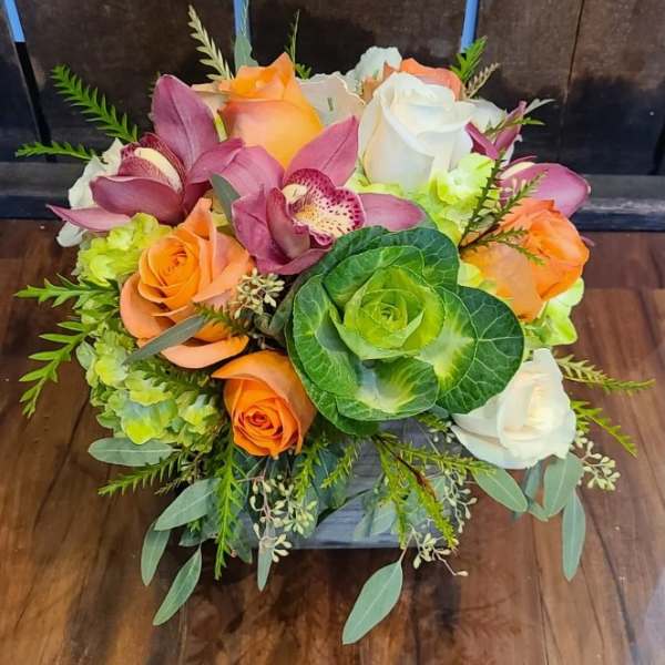 Bouquet of orange and white roses with purple orchids and green ornamental cabbage