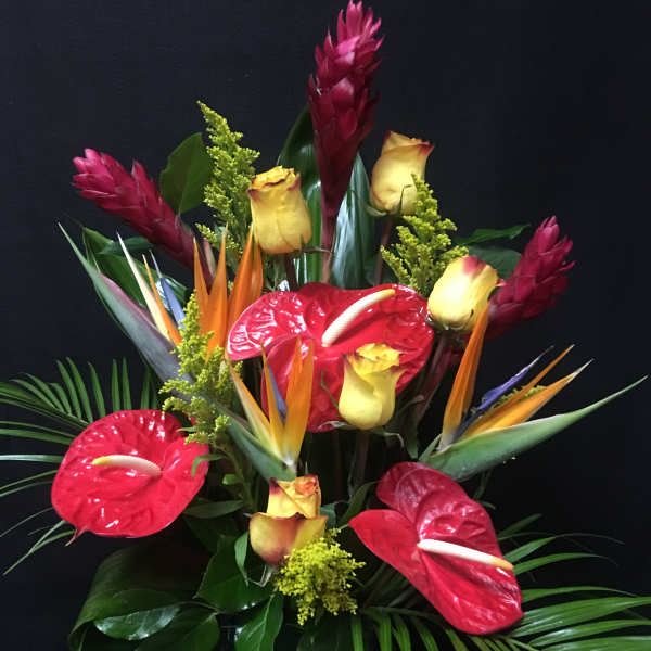 Tropical arrangement with red anthuriums, yellow roses, and bird of paradise