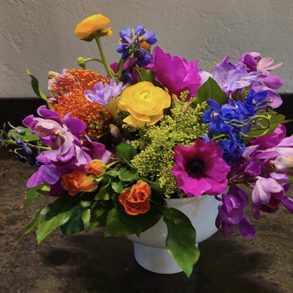 Colorful mixed flower arrangement in a white pedestal vase