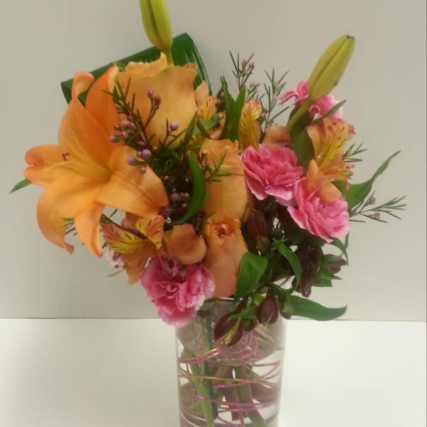 Orange lilies and pink carnations in a clear glass vase