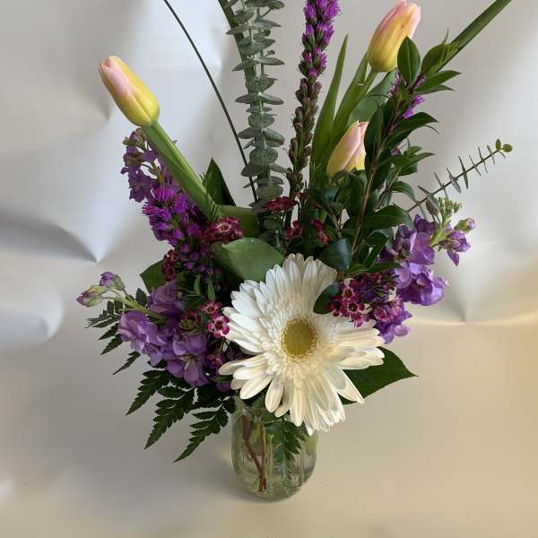 Mixed bouquet with white daisy and pink tulips in a glass vase