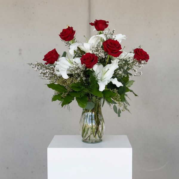 Red roses and white lilies arranged in a clear glass vase