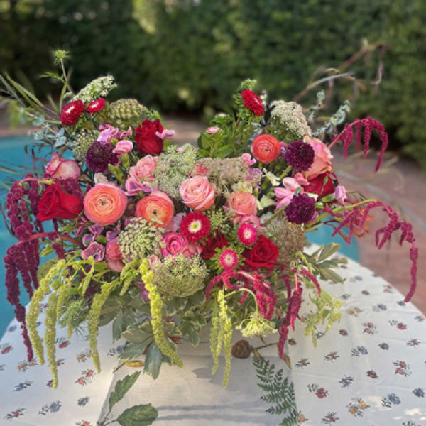 Large mixed bouquet of pink, red, and purple flowers in a white container