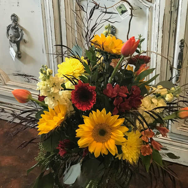 Bright mixed bouquet with sunflowers, tulips, and red blooms in a glass vase