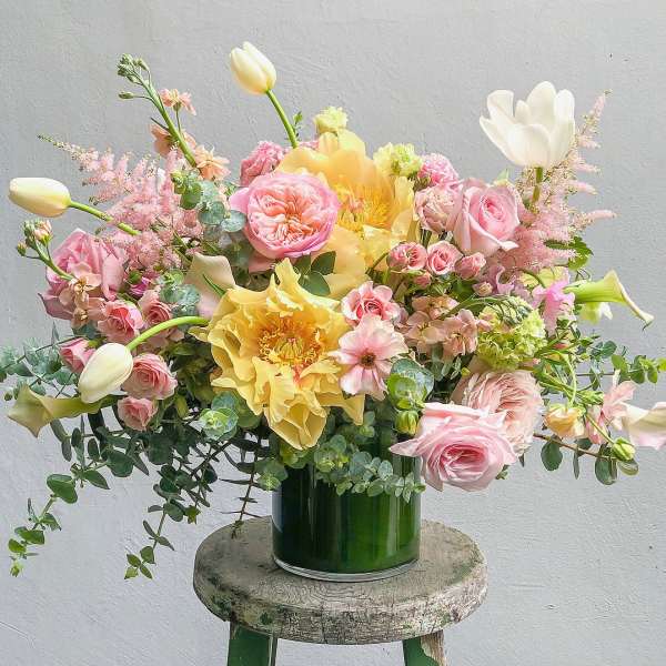 Pink and yellow floral arrangement in a green vase
