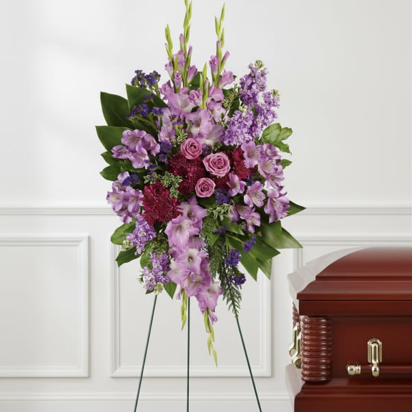 Purple floral standing spray beside a casket