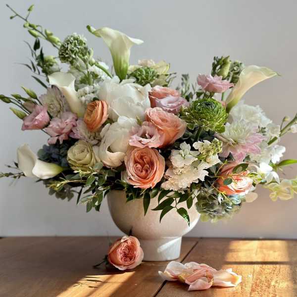 Pastel floral arrangement in a white vase with roses and calla lilies