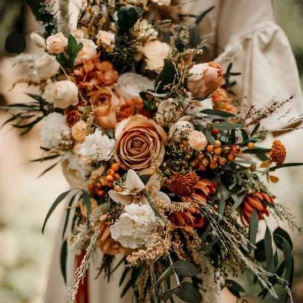 Large bouquet of peach and cream flowers with dark greenery