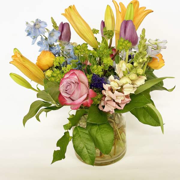 Mixed bouquet with roses, lilies, and snapdragons in a glass vase