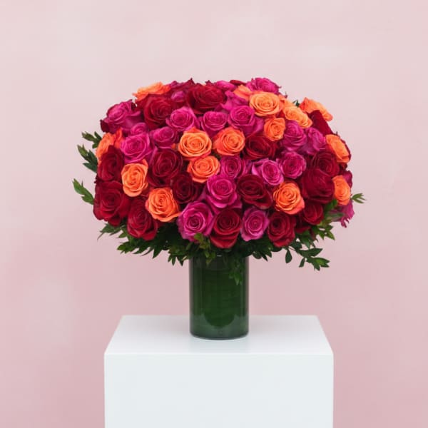 Bouquet of red, pink, and orange roses in a green glass vase