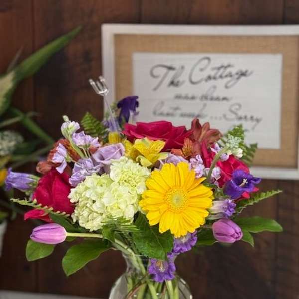 Mixed bouquet in a clear glass vase with yellow and pink blooms