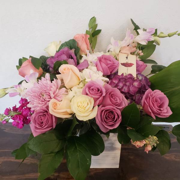 Pink and cream roses with purple blooms in a white vase