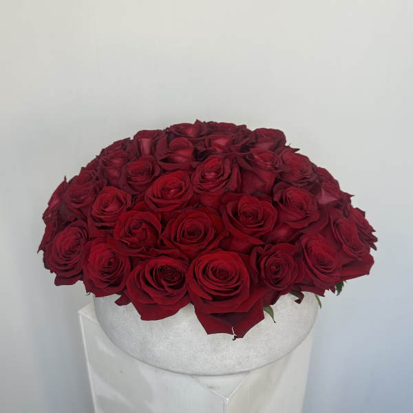 Round arrangement of red roses in a white hat box