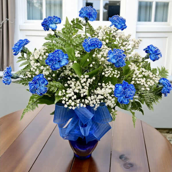 Blue carnations and white baby's breath in a glass vase with a blue ribbon