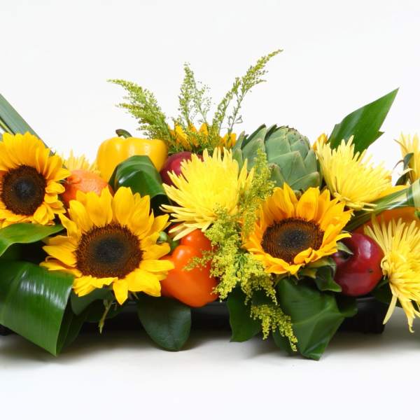Low floral centerpiece with sunflowers and gourds in a rectangular container