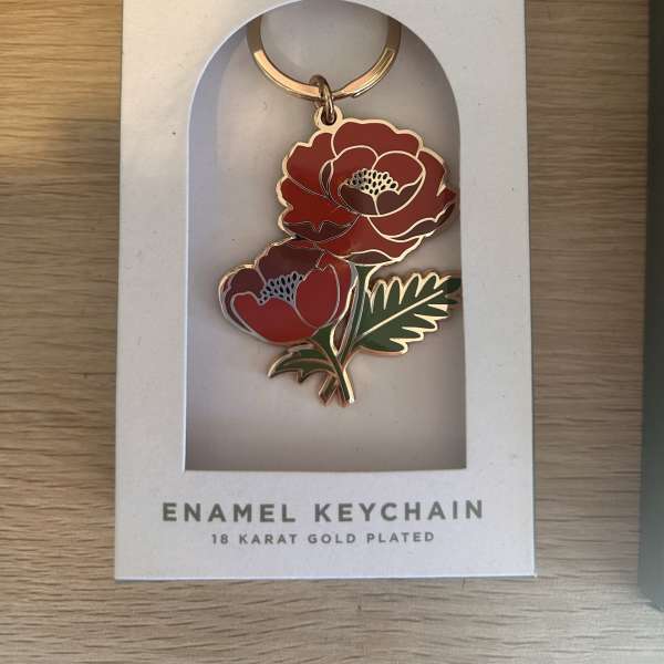 Red floral enamel keychain in a white retail box