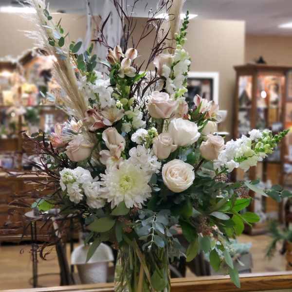 Tall bouquet of white and blush flowers in a clear glass vase