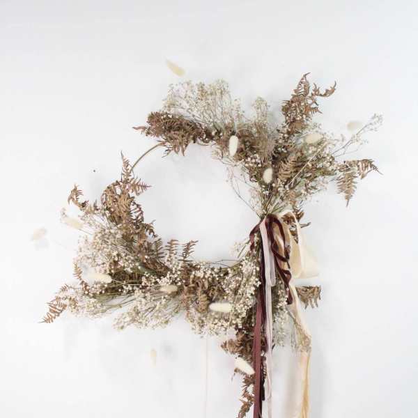 Dried floral wreath with ribbons on a white wall