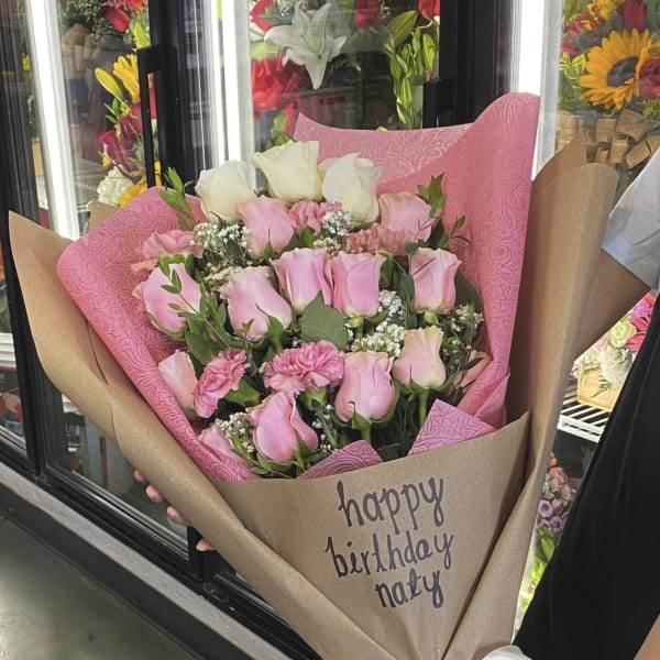 Pink and white rose bouquet wrapped in brown paper with a ribbon