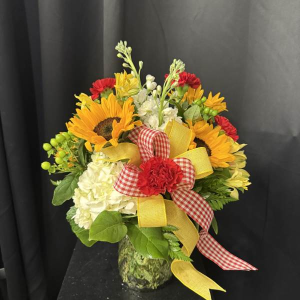 Bouquet of sunflowers, white hydrangeas, and red carnations in a glass vase