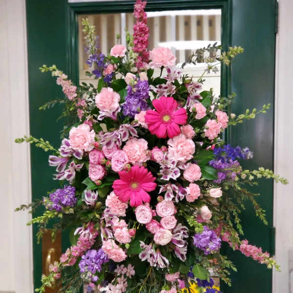 Tall pink and purple floral standing arrangement on a frame