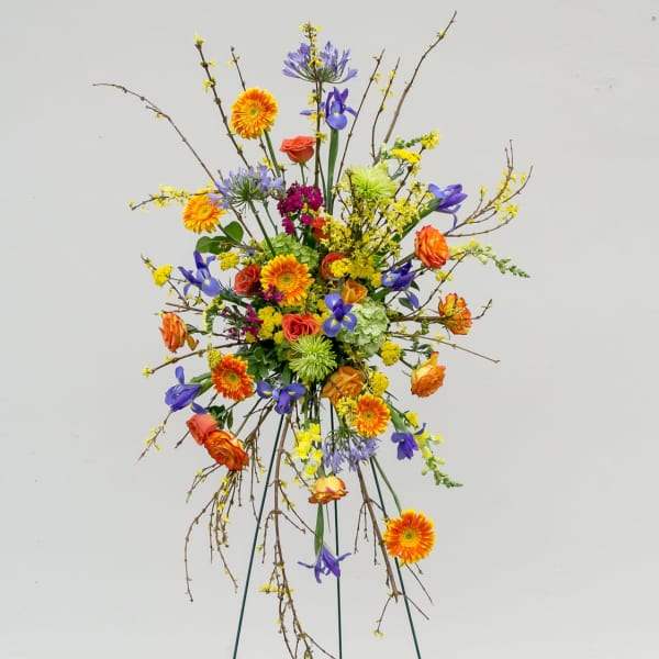 Tall mixed flower arrangement with orange, purple, yellow, and green blooms