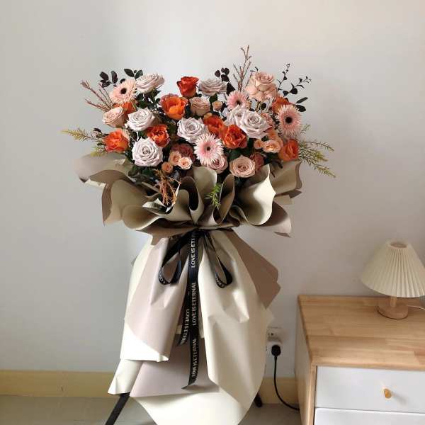 Large bouquet of peach and pink roses with paper wrapping