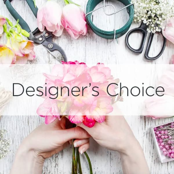 Hands holding a pink flower bouquet with floral tools on a table