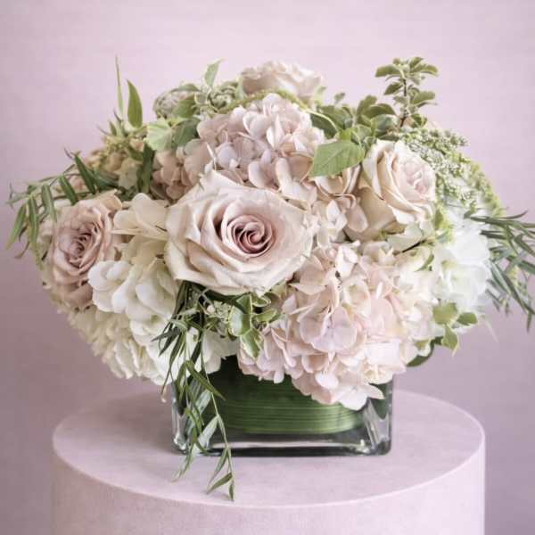 Blush roses and pale hydrangeas in a square glass vase