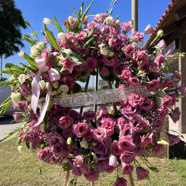 Large pink floral wreath on an easel with a ribbon banner