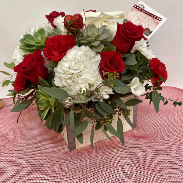 Red roses and white flowers in a wooden box with succulents