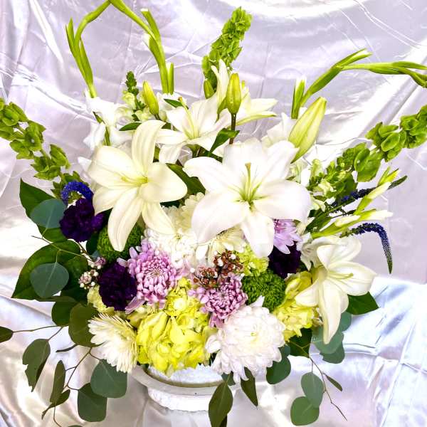 White lilies and mixed flowers arranged in a white vase