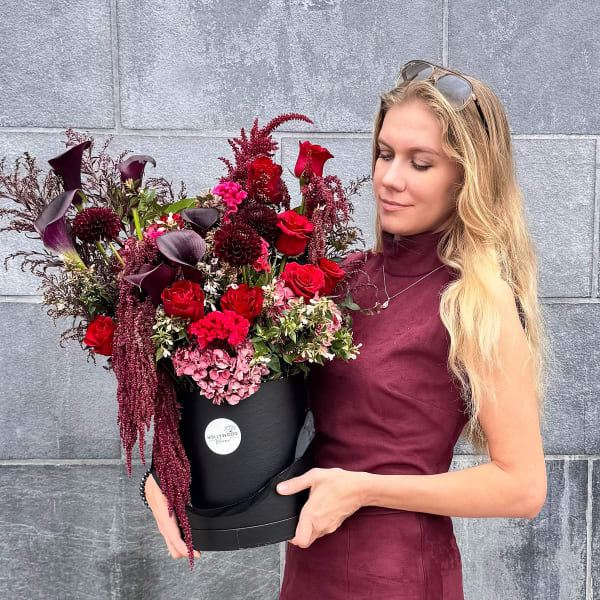 Woman holding a black box of red and burgundy flowers