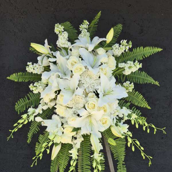 White floral standing spray on a wooden easel