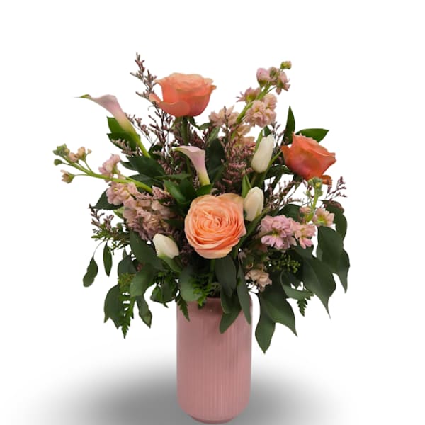 Peach roses and pink flowers arranged in a pink vase