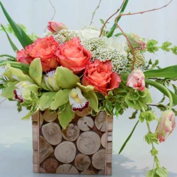 Coral roses and green orchids in a square wood vase