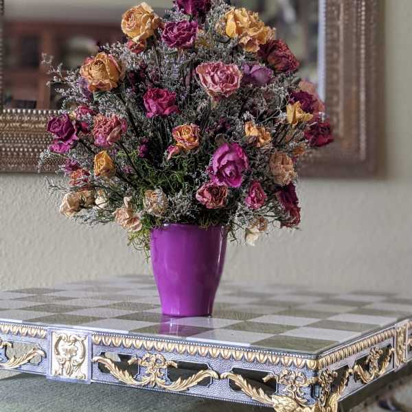 Bouquet of dried roses in a purple vase