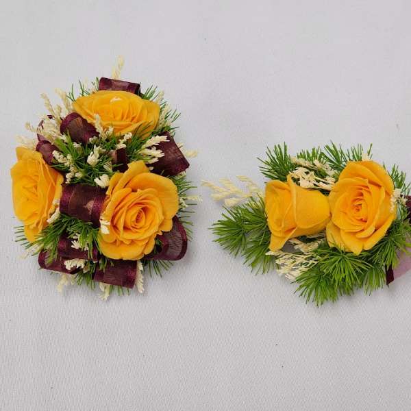 Yellow rose boutonnieres with burgundy ribbon and greenery