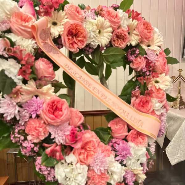 Heart-shaped floral wreath with pink and white flowers and a ribbon