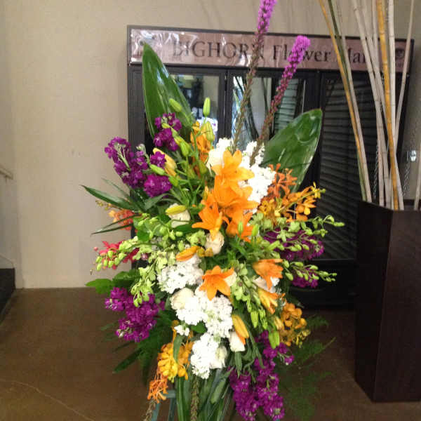 Tall standing floral spray with orange, purple, white, and yellow blooms