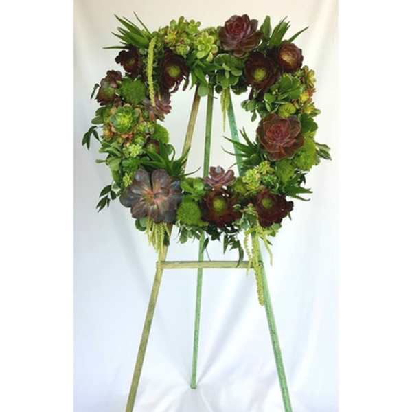 Succulent wreath on a standing easel with green and burgundy blooms