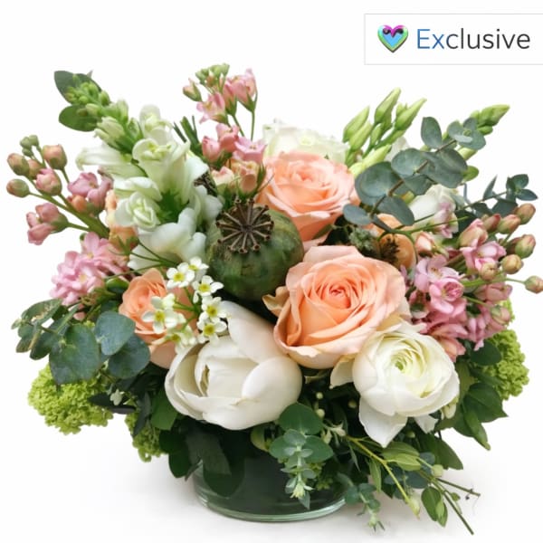 Peach and white roses in a glass vase with pink filler flowers
