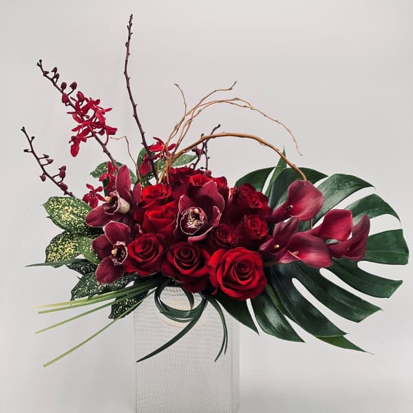 Red roses and burgundy orchids in a white vase