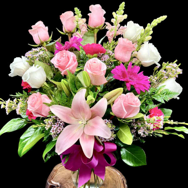 Pink and white rose bouquet with a large pink lily in a glass vase
